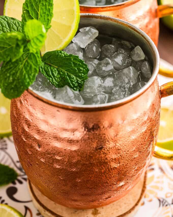 single moscow mule cocktail in a copper mug, garnished with mint and lime.