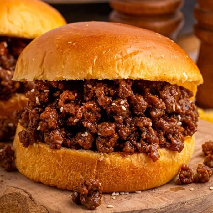 close up photo of an asian-style sloppy joe sandwich on wooden cutting board.