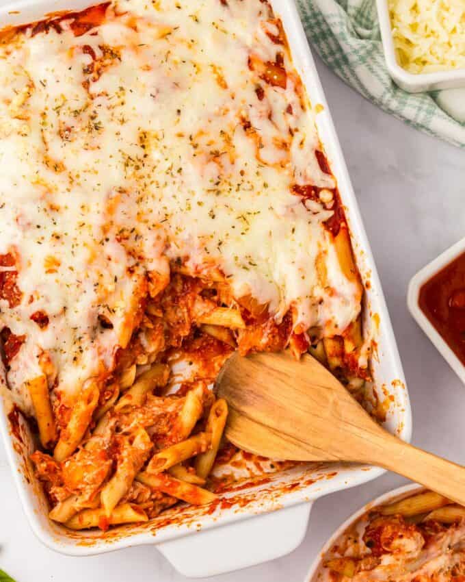 scooping out a serving of chicken parmesan casserole from the baking dish.