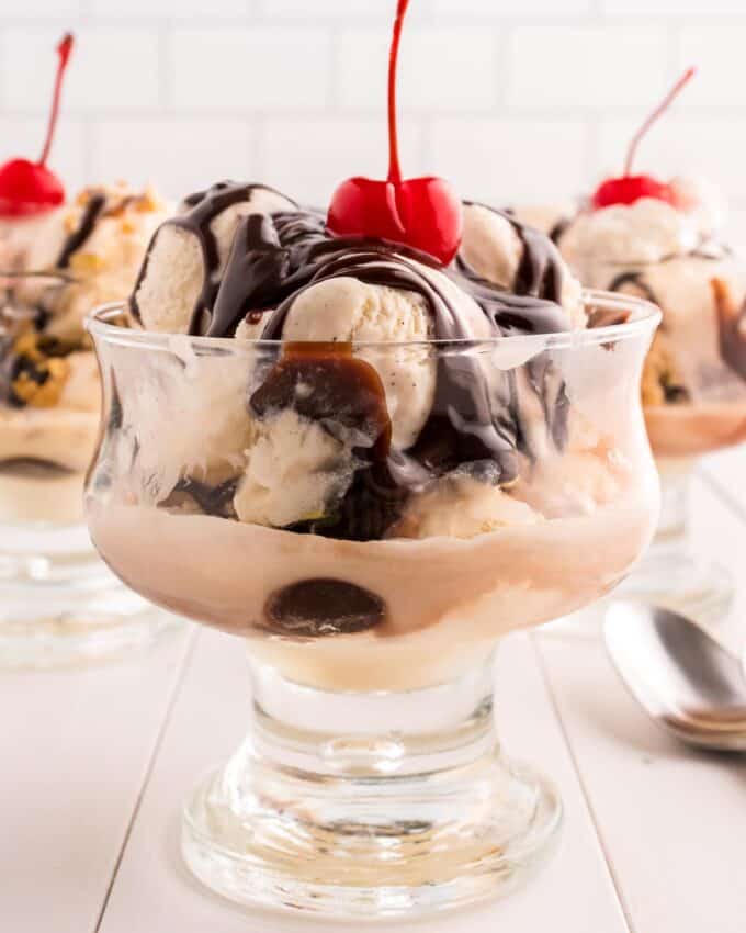 sundae bowl with vanilla ice cream, hot fudge sauce, and a cherry.