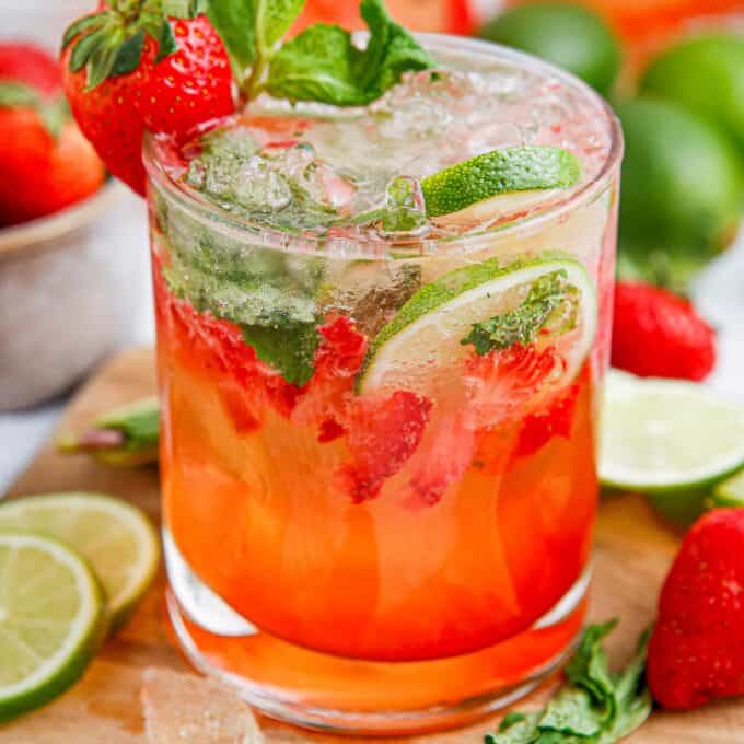 glass full of strawberry mojitos on a wooden cutting board.