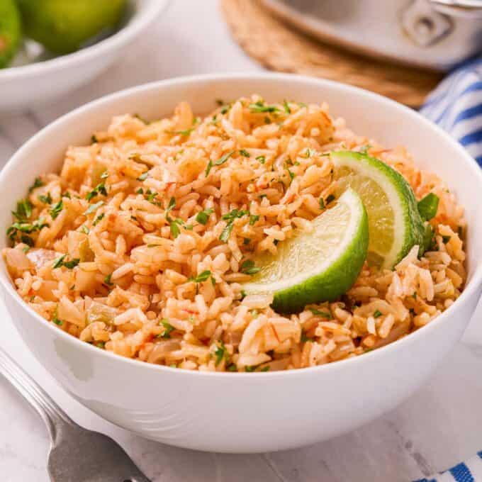 white bowl of Mexican rice garnished with lime wedges