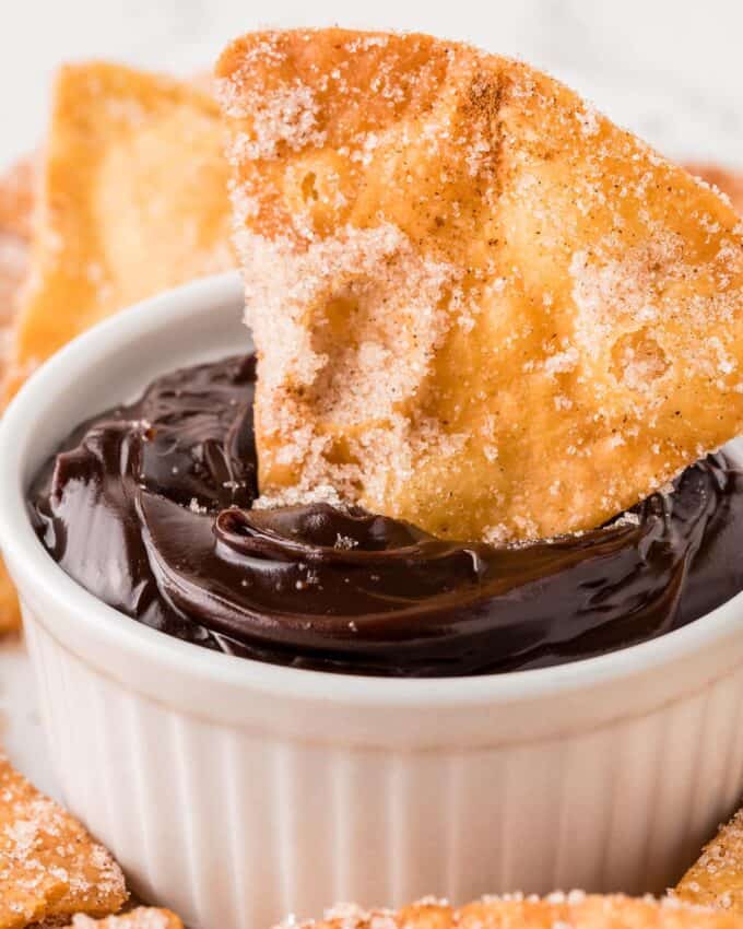 dipping a churro chip into a ramekin of chocolate sauce.