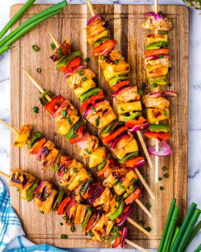 chicken skewers in a fan pattern on a wooden cutting board.