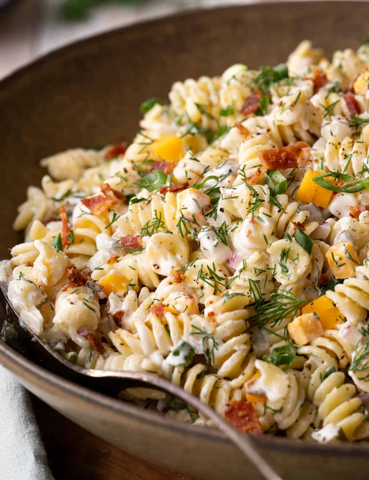 If you're a pickle lover, then I have the perfect pasta salad for you! Chopped dill pickles, bacon pieces, sharp cheddar, and crisp red onion, combined with pasta and an ultra-creamy dill pickle dressing! Perfect for summer cookouts and potlucks, and super easy to customize to your tastes.