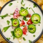 bowl of queso blanco garnished with tomatoes and jalapeños