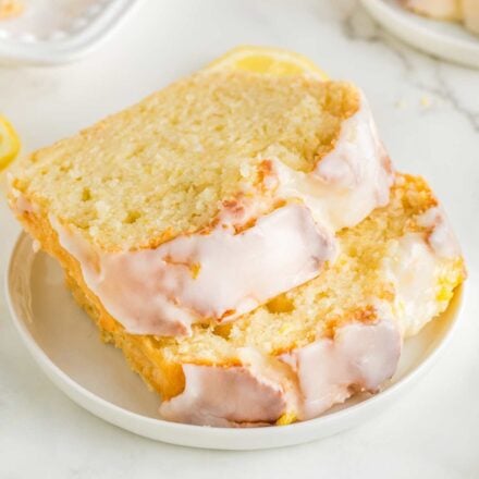 two slices of lemon loaf stacked offset on a white plate.