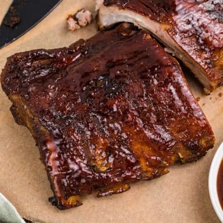 rack of ribs slathered in bbq sauce on a piece of parchment paper