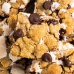 s'mores chocolate chip cookie bars stacked on a plate.