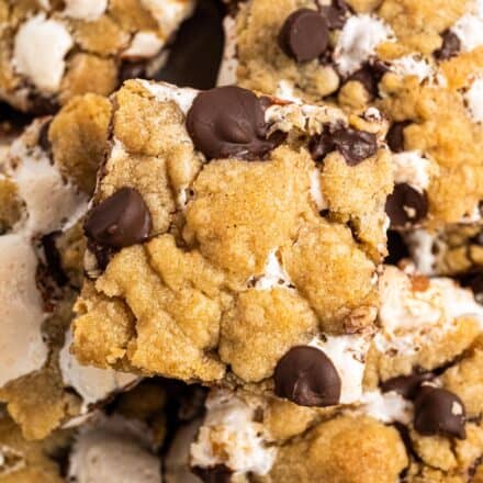 s'mores chocolate chip cookie bars stacked on a plate.