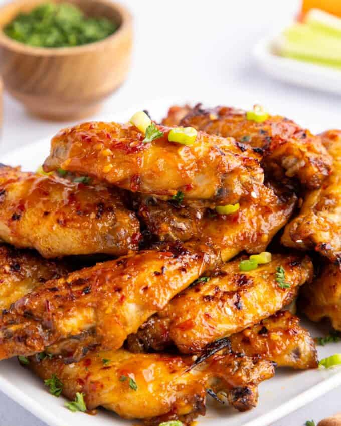 sweet chili chicken wings piled on a white plate.