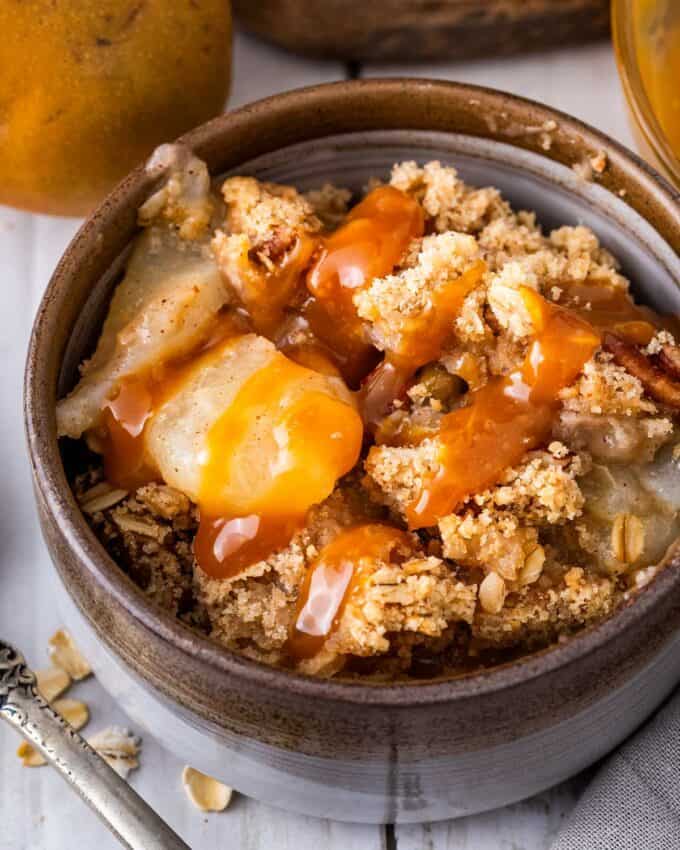 pear crisp in bowl and drizzled with caramel sauce