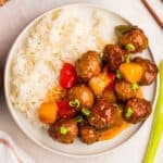 overhead photo of sweet and sour meatballs with white rice on a white plate