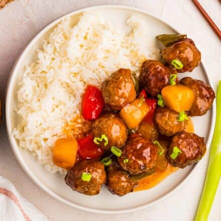 overhead photo of sweet and sour meatballs with white rice on a white plate