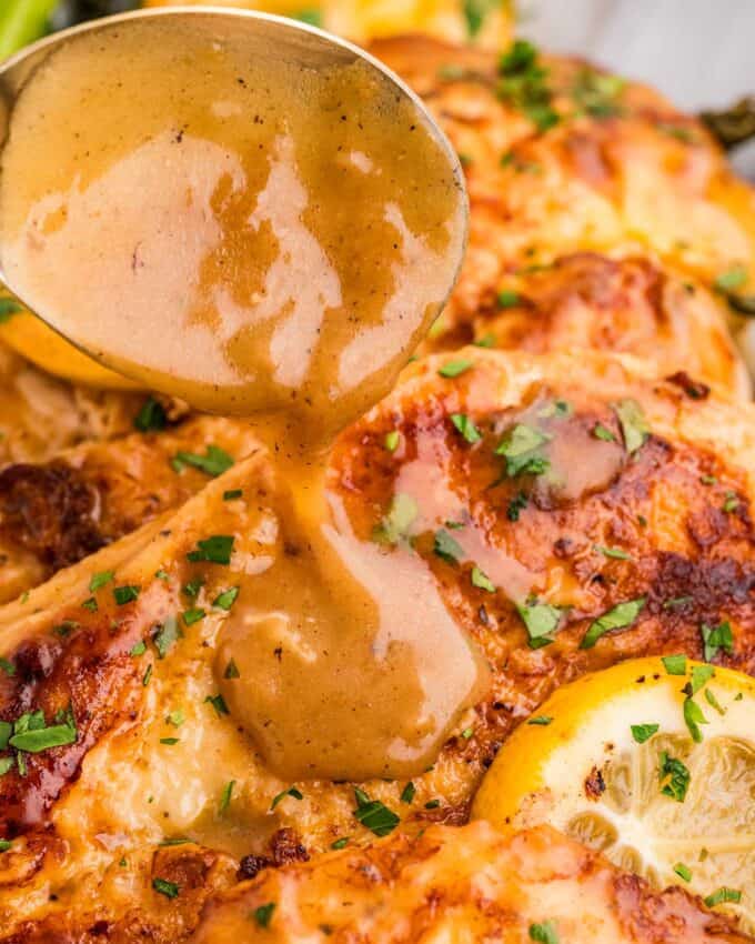 spooning white wine lemon butter sauce over tender pieces of chicken.