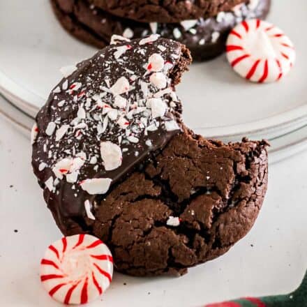 chocolate peppermint cookie with a bite taken out of it, resting by a stack of plates.