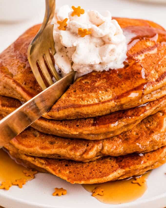 cutting into a stack of gingerbread flavored pancakes