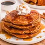 stack of gingerbread pancakes with syrup and whipped cream