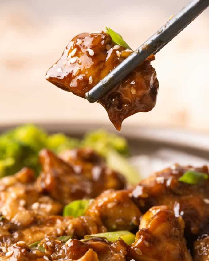 chopsticks holding a piece of teriyaki chicken
