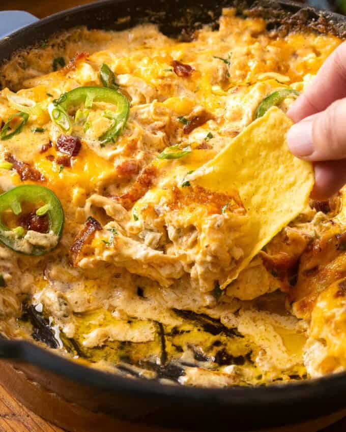 scooping chicken jalapeno popper dip with a tortilla chip