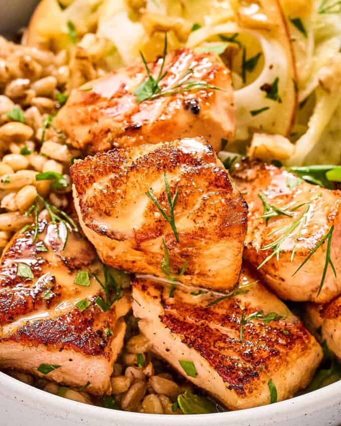 close up of cooked salmon bites in a grain bowl.