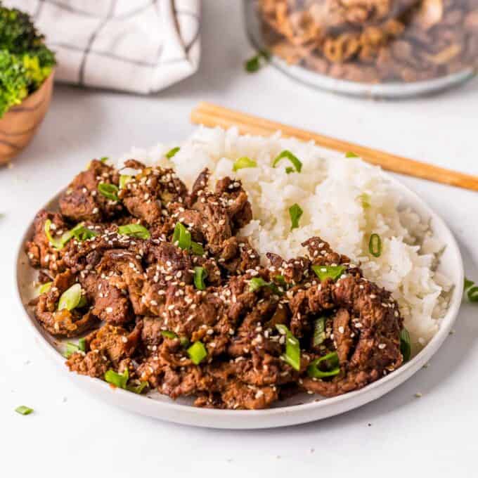 white plate with rice, beef bulgogi, and green onions