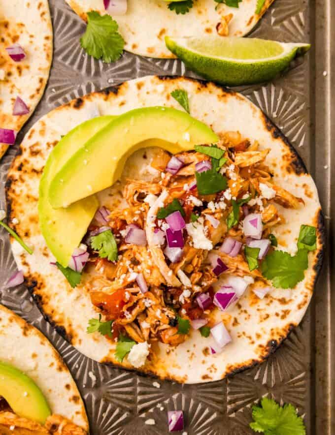 These easy chicken tinga tacos are made with tender and juicy shredded chicken that's simmered in a bold and smoky chipotle sauce! The chicken is perfect in tacos, burritos, enchiladas, nachos, and more!