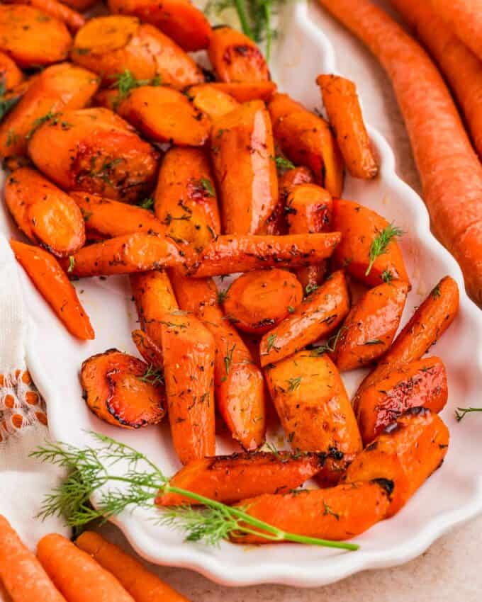 roasted carrots on a white platter with fresh dill and honey