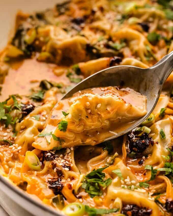 spoonful of baked dumplings in a red curry coconut sauce