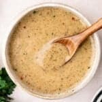 white bowl of italian dressing with a wooden spoon