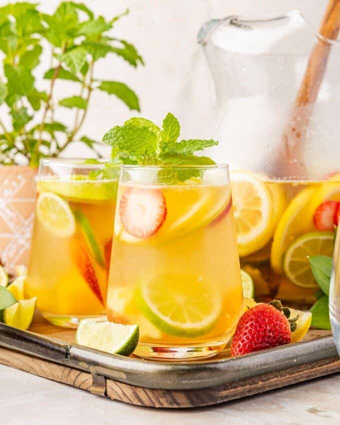 tray filled with a pitcher of sangria and several glasses of white sangria