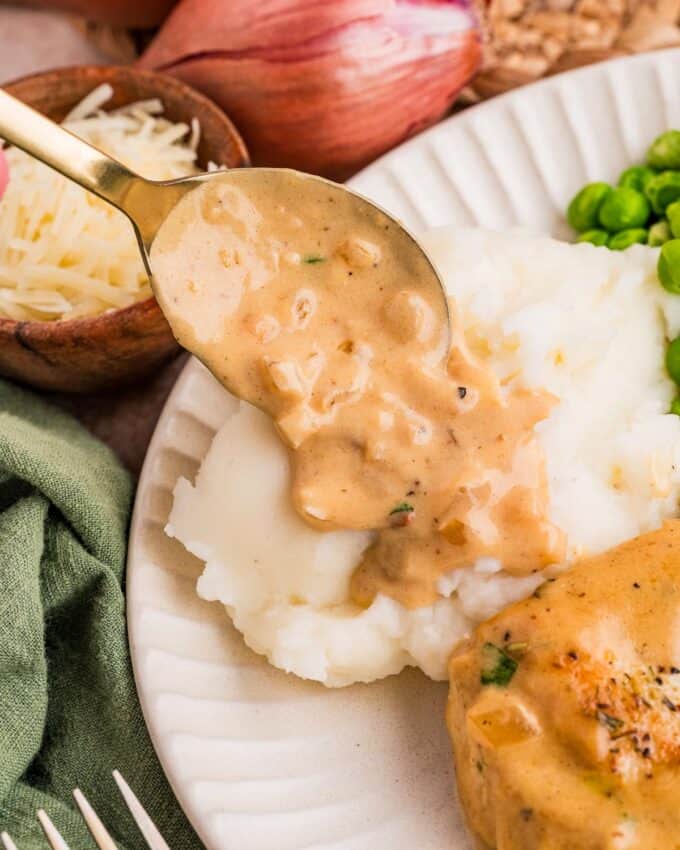 spooning dijon gravy over mashed potatoes