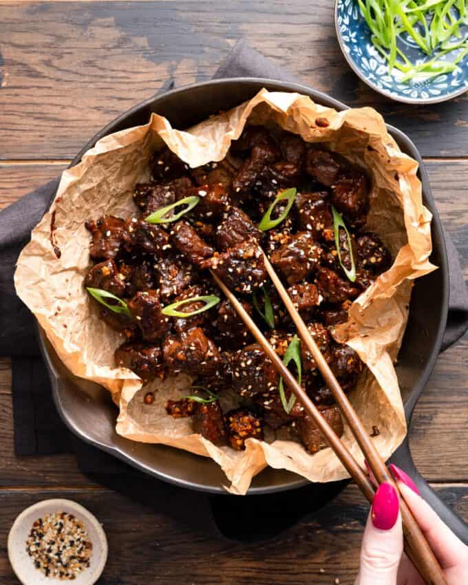 chopsticks picking up a steak bite from the skillet