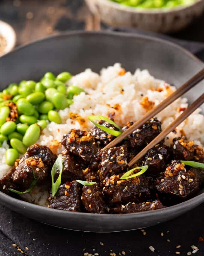 eating a miso soy steak bite with chopsticks