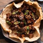 overhead photo of miso soy steak bites in a skillet with garnishes