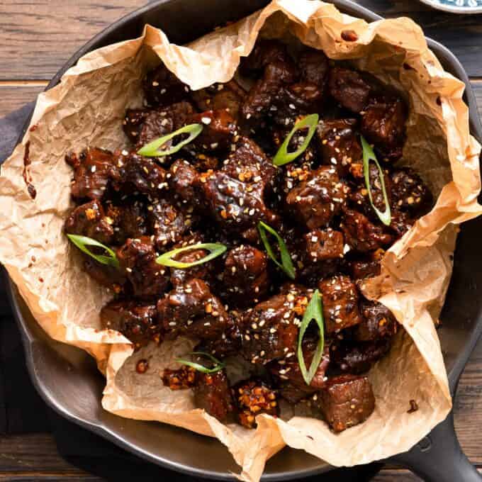 overhead photo of miso soy steak bites in a skillet with garnishes